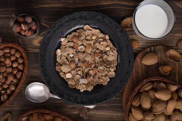 Flat lay of healthy breakfast with nuts and corn flakes on brown rustic background