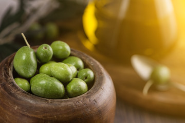 Wooden cup of olives with Extra virgin olive oil in glass bottle on rustic background. close up
