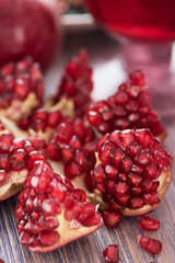 Fresh opened pomegranate with pomegranate juice in a glass on rustic wooden background