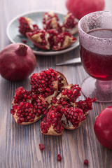 Pomegranate juice in a glass with fresh pomegranates around with scattered seeds on rustic wooden background 5