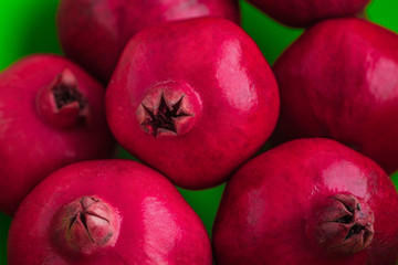 Fresh ripe red pomegranates close up view on green backdrop 2