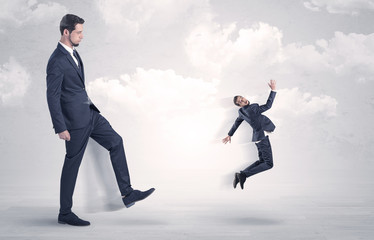 Fototapeta premium Big businessmen kicking himself as a small employee with cloudy background 