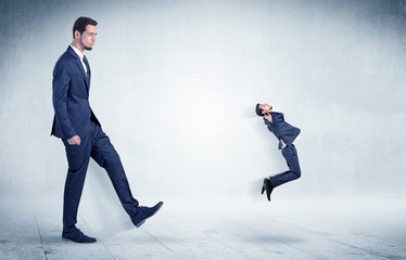 Big businessman kicking small businessman who is flying away with his briefcase on his hand
