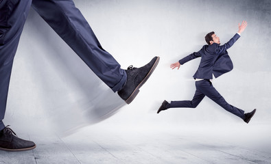 Giant leg kicking small businessman and he is flying away
