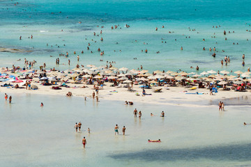 Fototapeta premium View over small sandy beach in beautiful Balos lagoon. Pink sand and shallow turquoise water. People enjoying on the beach. Mediterranean Sea. Chania, Crete island, Greece