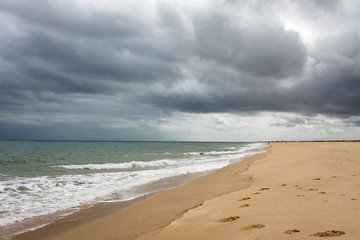 Sandy beach before the rain. Dark clouds over the ocean and the beach.