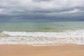 Fototapeta na wymiar Sandy beach before the rain. Dark clouds over the ocean and the beach.