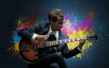 Obraz premium Young classical guitarist musician with colorful splotch wallpaper