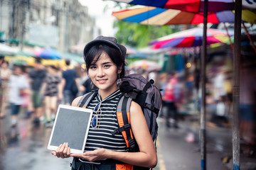 Young happy asian woman tourist in market shopping with tablet computer for online map.Traveling backpacker girl present screen of digital tablet outdoor .Travel tourism,technology concept. copy space