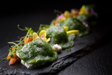 Dumplings with spinach green, on a dark wooden background, top view. with vegetables and cheese.