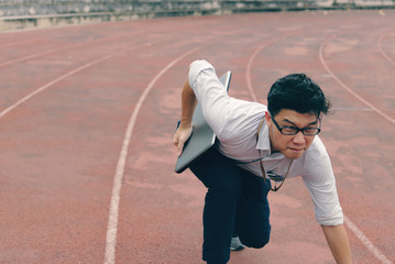 Competition business concept. Confident young Asian businessman with laptop ready run to forward on race track.