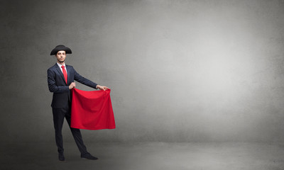Businessman standing with red toreador cloth in his hand in an empty room
