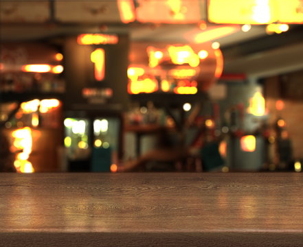 Blur bokeh background with empty wooden table top in night cafe