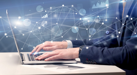 Businessman typing on laptop with linked reports charts grapghs around
