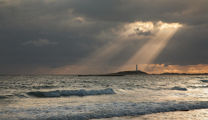 A ray of sunlight illuminates the Trafalgar lighthouse at sunset
