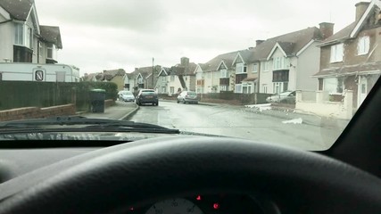 A dirty car windshield being cleaned using the screenwash fluid and wipers.
