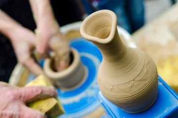 Street master class on modeling of clay on a potter's wheel In the pottery workshop. Focus on the vase, the process of making the vase blurred against the background