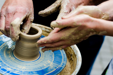 Creating a jar or vase of white clay close-up. Man hands making clay jug macro. The sculptor in the workshop makes a jug out of earthenware closeup. Twisted potter's wheel. Master crock.