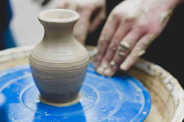 clay pot and hands that created it. Handmade vase making with wet clay and hand potter's wheel In the pottery workshop