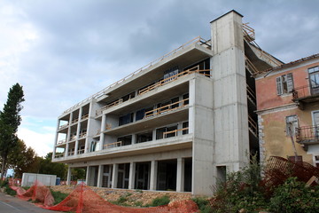 New hotel building under construction next to abandoned destroyed apartment building surrounded...