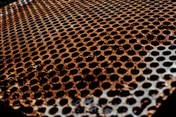 Perforated rusty iron sheet texture. Surface with depth of field, abstract industrial mesh background