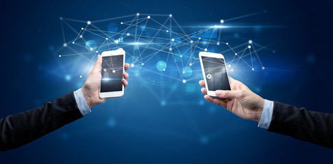 Close up of two hands holding smartphones and sharing business data