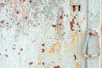 Texture of old rusty metal door with handle, painted white which became orange from rust in some places. Horizontal texture of cracked white paint on rusty steel