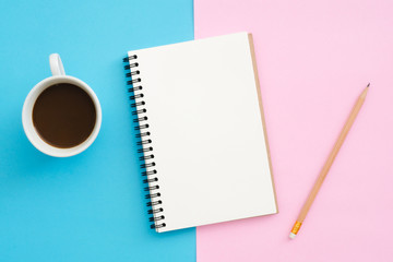 Creative flat lay photo of workspace desk. Top view office desk with pencil, notebook and coffee cup on blue pink color background. Top view with copy space, flat lay photography.