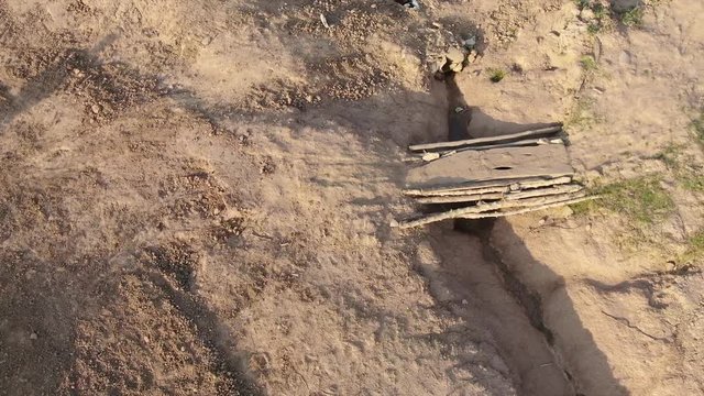 Aerial drone view fly over a rural dirt road used for adventure travel and off road extreme sports in rural Southeast Asia. Camera then lifts and tilts to reveal fields and panorama with farms and ric