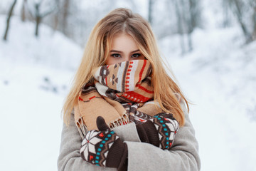 Merry young happy woman with amazing brown eyes in a stylish warm gray coat in vintage mittens in...