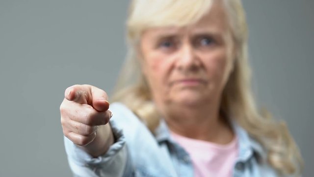 Angry old woman pointing by finger in camera, condemnation gesture, disapproval