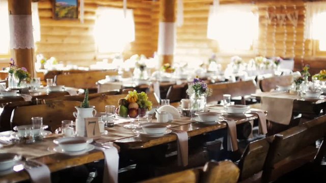 Horizontal Panorama of Wooden Banqueting Hall Decorated in Boho Style with Served Dining Tables