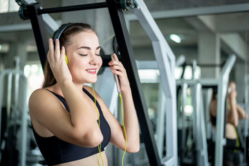 Fototapeta na wymiar Young sporty fit caucasian woman using smartphone listening music and texting while taking a break in fitness gym .Sport fitness, lifestyle workout and technology for healthy concept