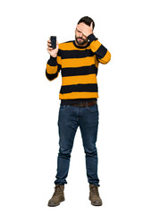 Full-length shot of Handsome man with striped sweater with troubled holding broken smartphone on isolated white background