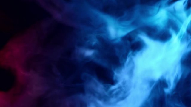 red and blue smoke patterns moving moving against at dark background 