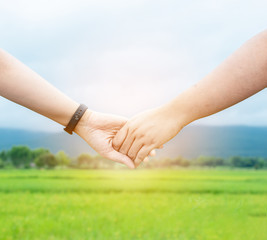 Close up of hands Two friends having fun hold hand travel on the green field  in nature background together .Traveler friendship concept .