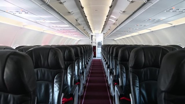 4K Interior of commercial airplane cabin with black and red passenger seats.