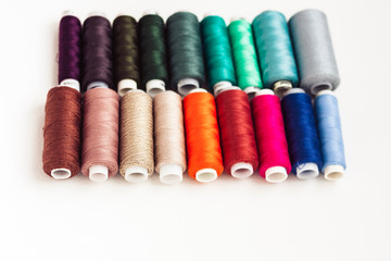 Colored sewing thread coils on white background with copy space for text.