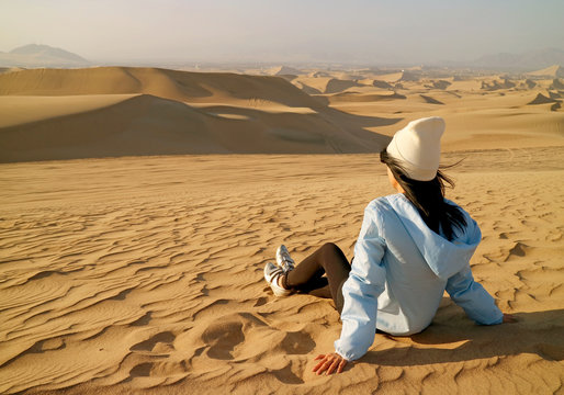 A female tourist resting on the sand dune of Huacachina desert in Ica Region, Peru, South America