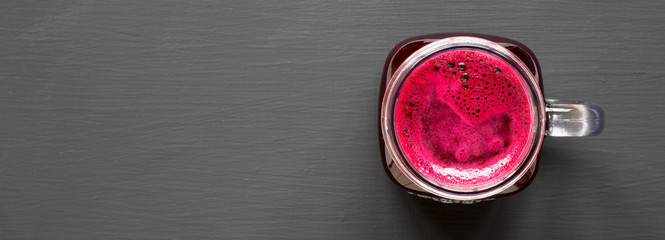 Beetroot smoothie in glass jar mug over black background, overhead view. Flat lay, top view. Space for text.