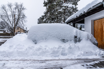 Von Schneemassen umgebenes Auto in der Garageneinfahrt
