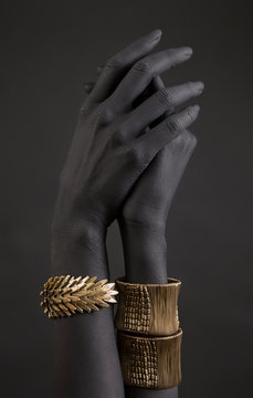Black woman's hand with gold jewelry. Oriental Bracelets on a black painted hand.