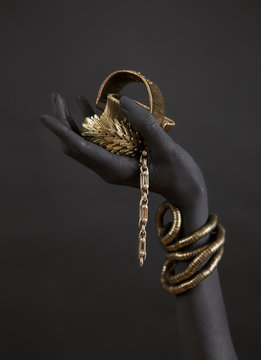 Black woman's hand with gold jewelry. Oriental Bracelets on a black painted hand.