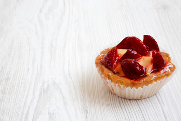 Strawberry vanilla cream cheese tarts on white wooden background, low angle view. Copy space.