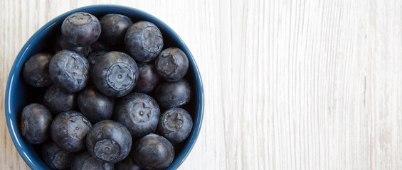 Blueberries in a blue bowl, overhead view. Organic superfood. Space for text.