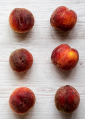 Fresh peaches on white wooden background, top view. Overhead, from above. Close-up.