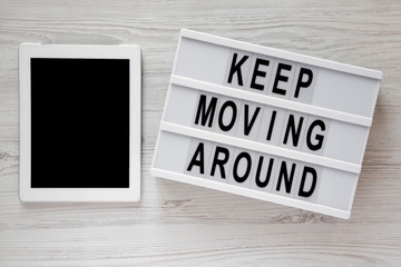 'Keep moving around' words on modern board, tablet on a white wooden surface, top view. From above, flat lay, overhead.