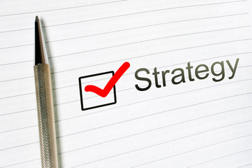 Strategy word written on lined paper. Strategy concept. Checkbox and pen