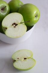 green apples in a white plate on a white background.