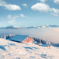 Fantastic winter landscape with wooden house in snowy mountains. Christmas holiday concept